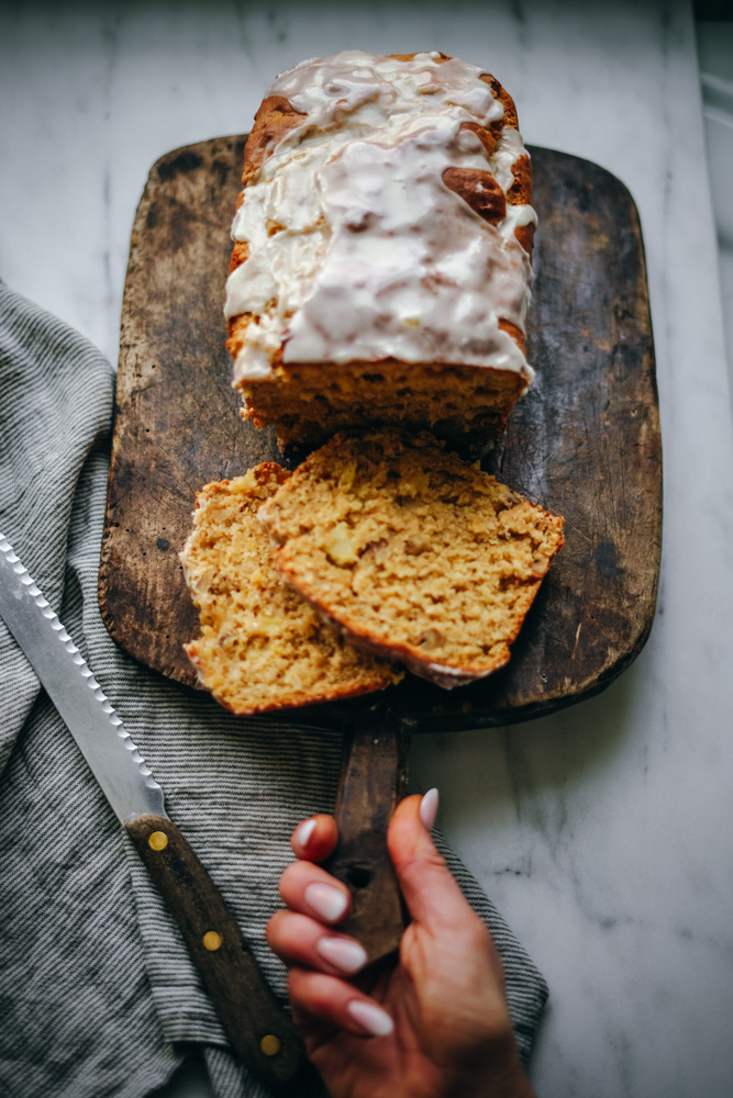 A beautiful loaf of pineapple bread that has been sliced and is being served on a wooden cutting board.