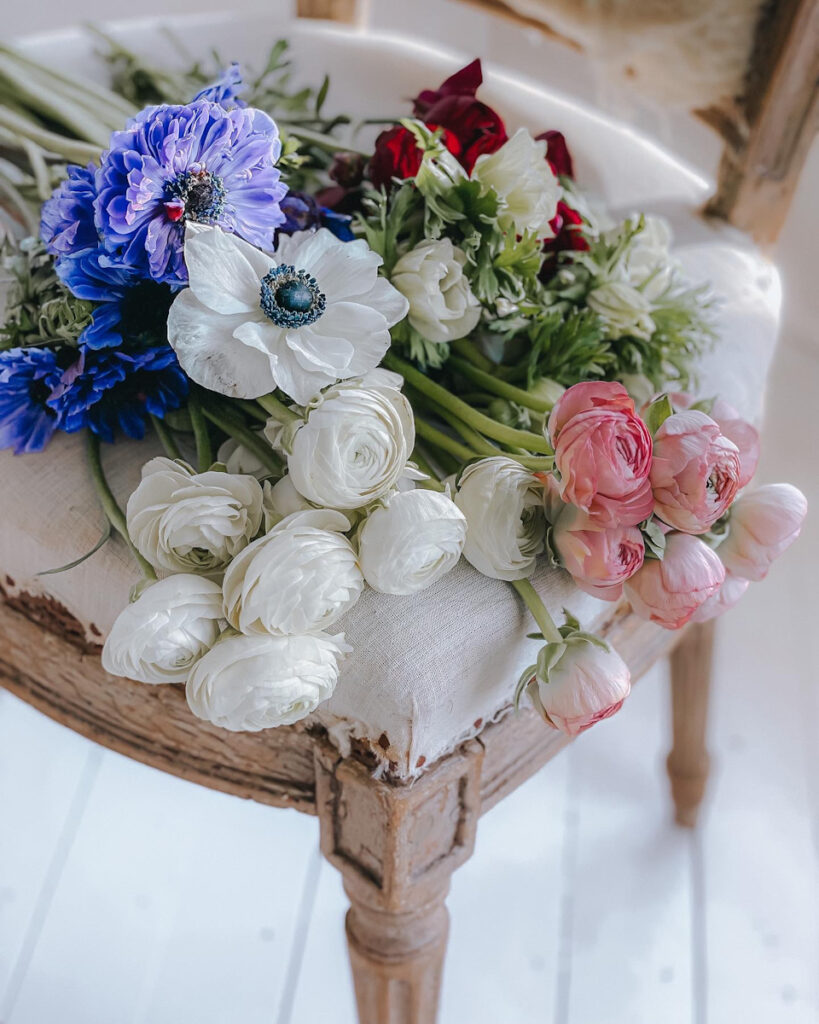 Beautiful display of ranunculus, anemones and tulips on an antique chair.