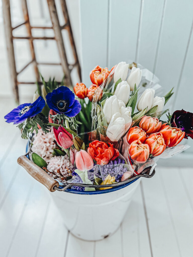 Large white enamel bucket full of spring flowers.