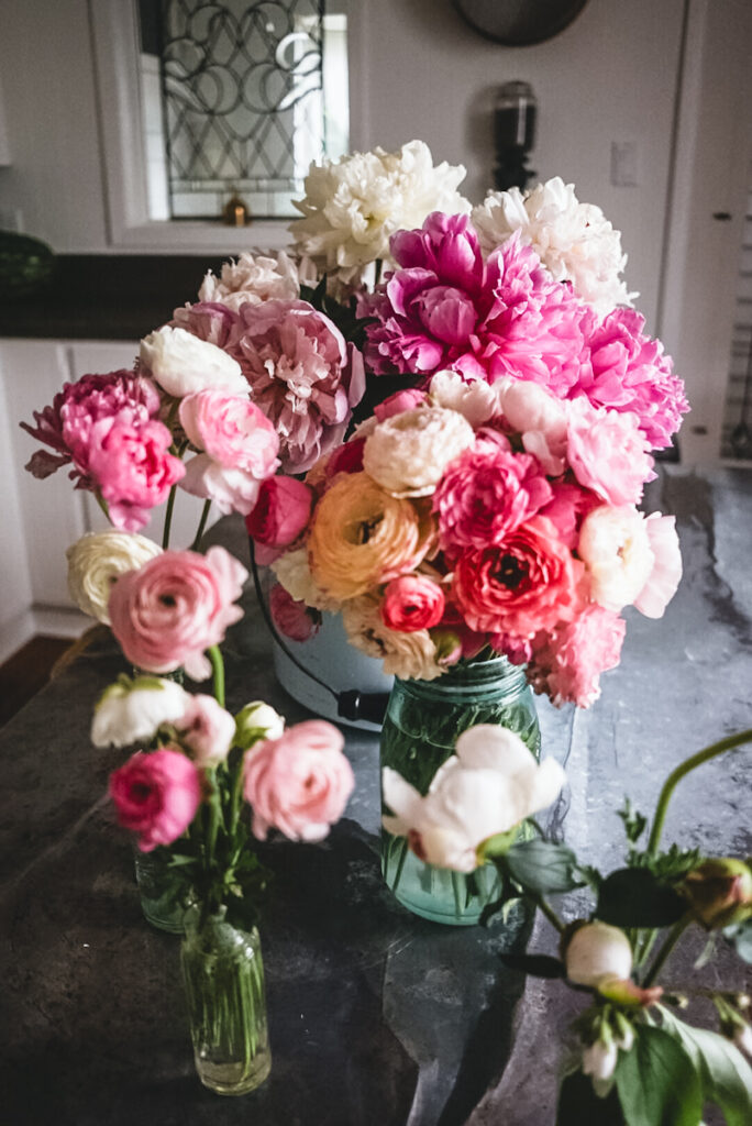 Peonies and ranunculus flowers all arranged in vases.