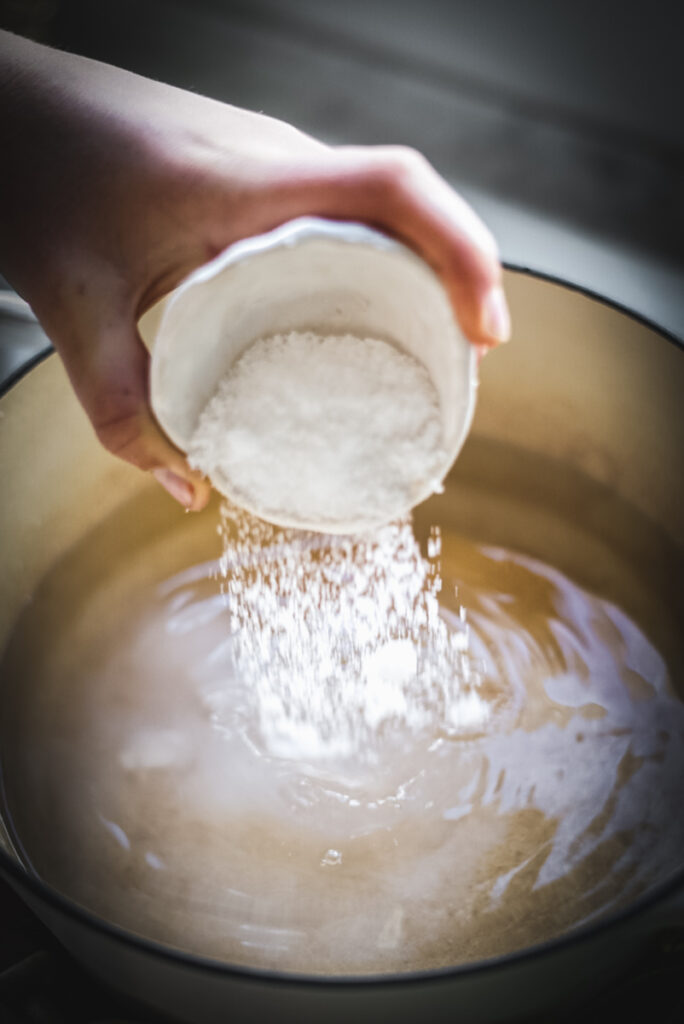 Adding salt to the brine to make dill pickles.