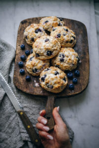 Blueberry scones being served on a vintage wooden tray with blueberries around them.