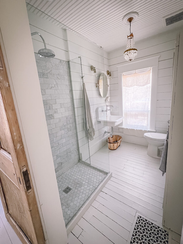 A beautiful vintage style bathroom with a French chandelier and a Carrara marble shower. 