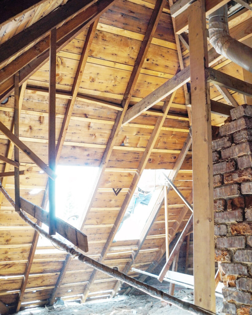 Two large skylights cut into the roof line of an unfinished attic space. 