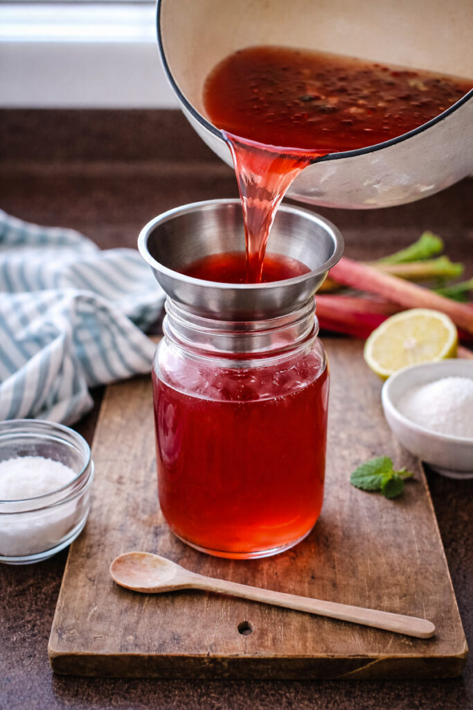 Pouring the rhubarb syrup into a mason jar. 