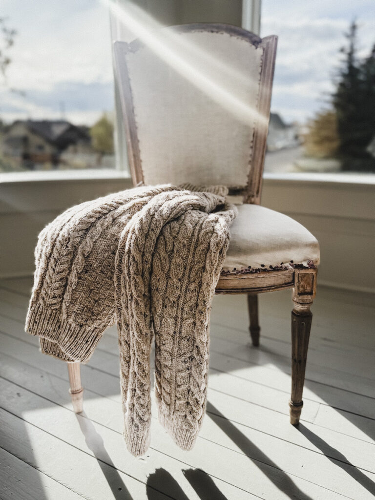 An antique wool sweater layered on top of an antique chair.