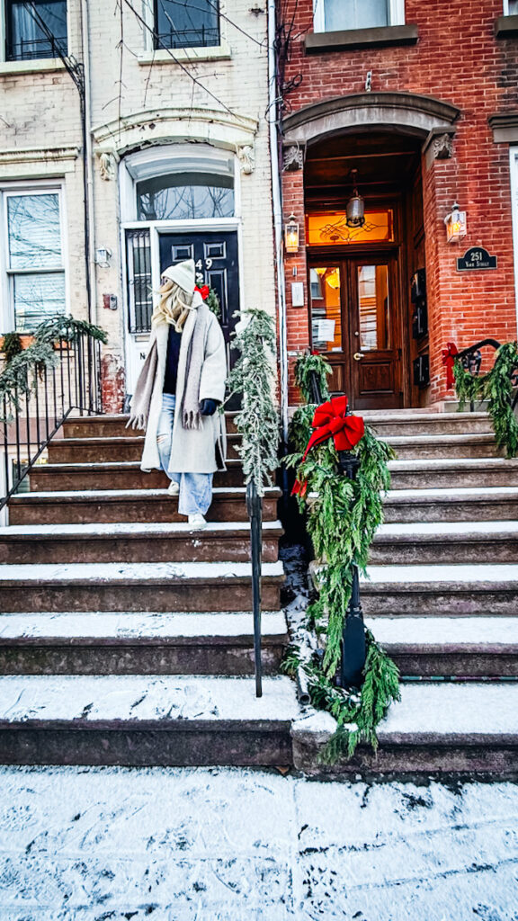 Deborah walking outside of a beautiful brick town house in NYC to go antique shopping.
