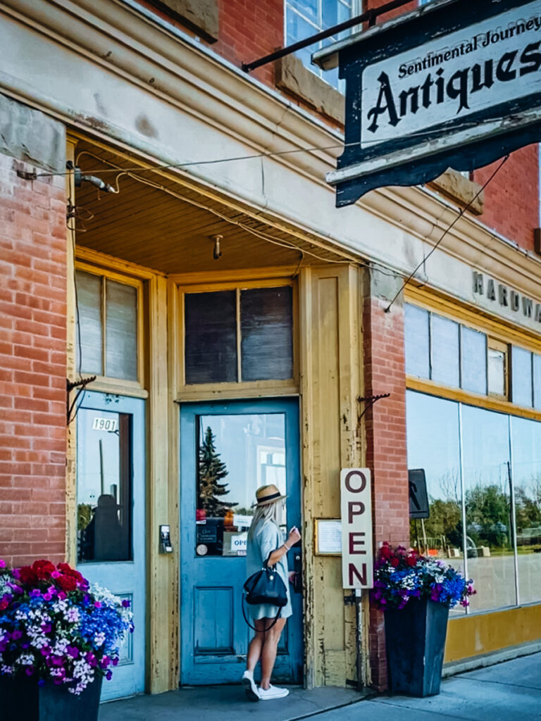 Deborah from Be Vintage Style walking into an antique store with a brick exterior and a blue door.