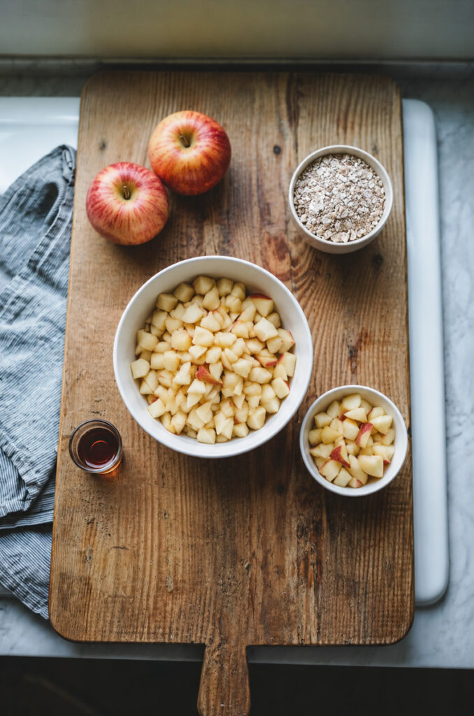 Apples that have been sliced and cubed. Maple syrup and an oat crumble topping, ready to be made into an easy apple crumble. 
