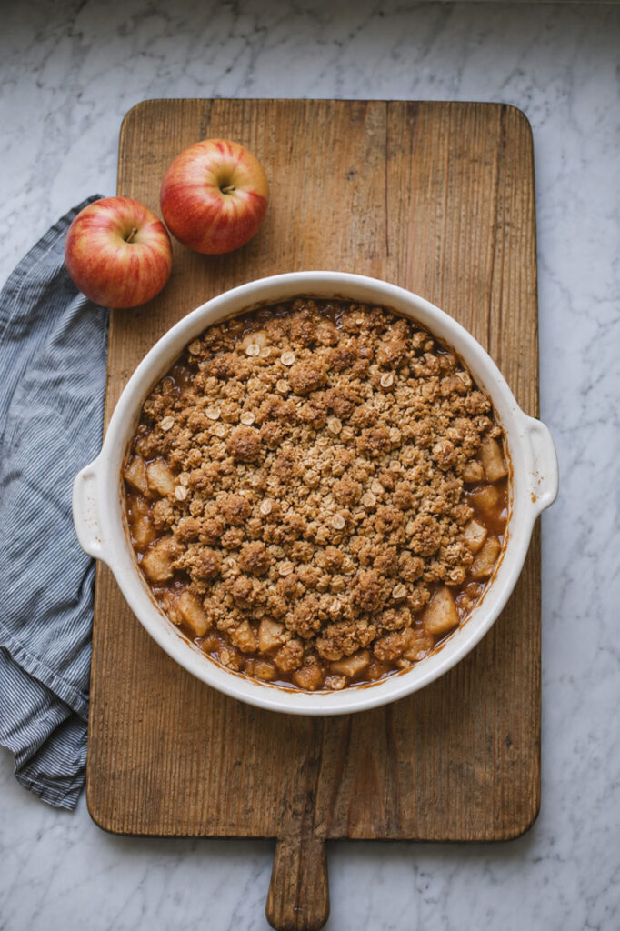 A warm and delicious apple crumble on an anti-cutting board and marble countertop. 