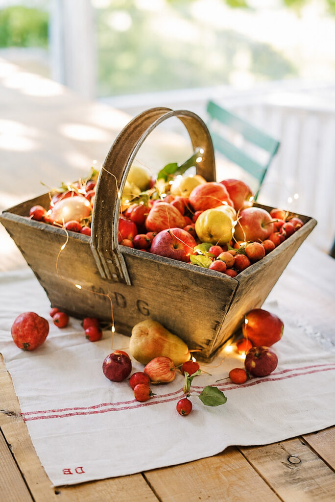 A basket full of fresh-picked apples that has twinkling lights spread through it to give a glow for Hygge in Autumn.