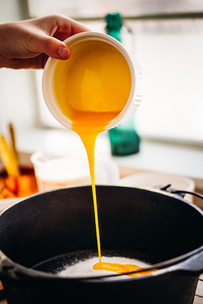 Combining whisked egg yoke and white sugar in a cast iron pot.