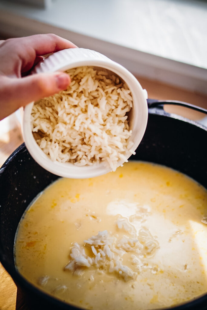 Adding rice into a cast iron pot to a sugar and egg mixture to make baked rice pudding.