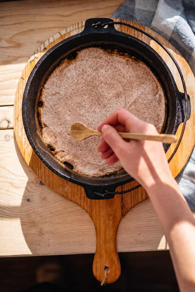 Freshly baked rice pudding in a cast iron pot getting ready to be sliced and scooped into a bowl.