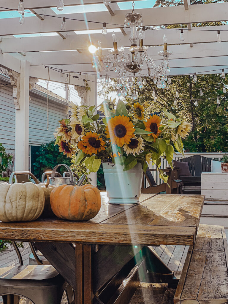 Beautiful bouquet of sunflowers on a back porch with pumpkins on the table.
