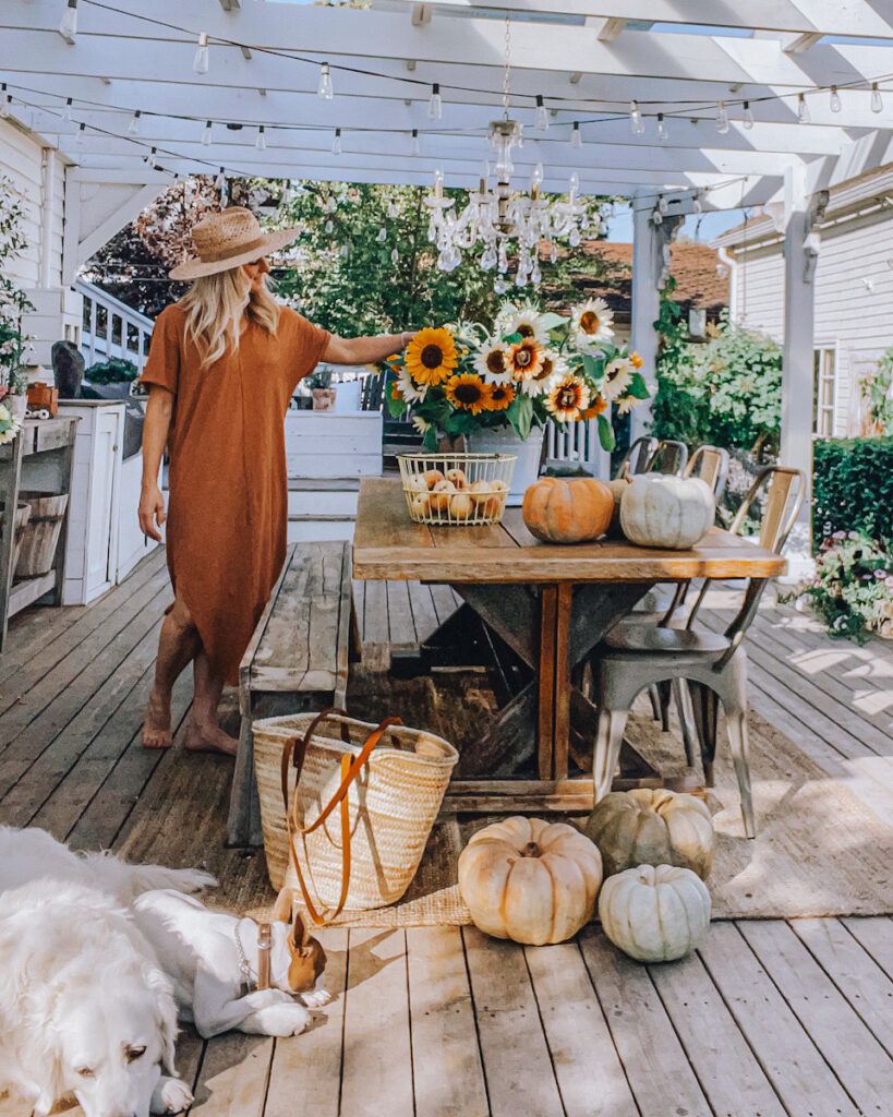 Deborah McDonald on her back deck with sunflower arrangement and beautiful pumpkins beside her farmhouse table.