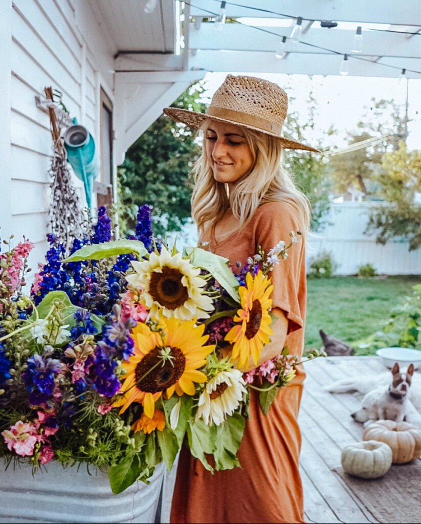 Deborah McDonald, B Vintage Style, holding a bundle of fall flowers, including sunflowers.