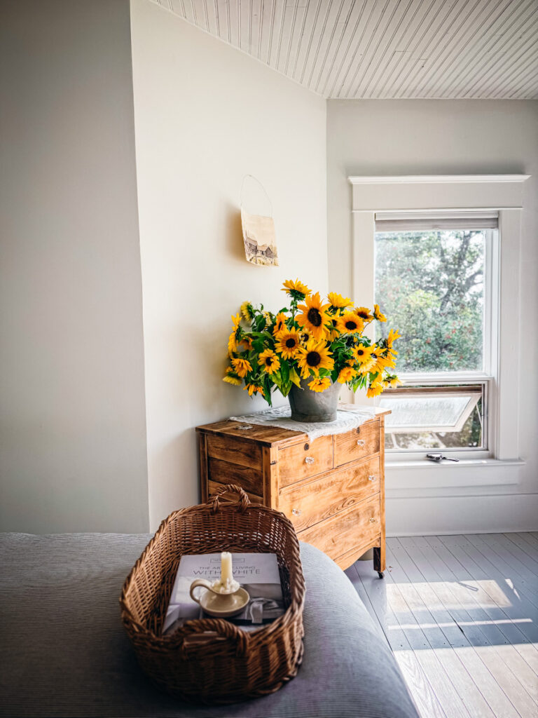 Sunflowers arranged in an antique galvanized bucket in a bedroom.