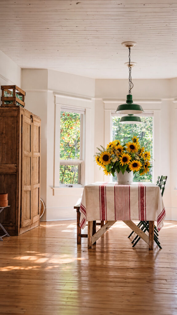 Sunflowers on a dining room table with a linen tablecloth that has red stripes on it.