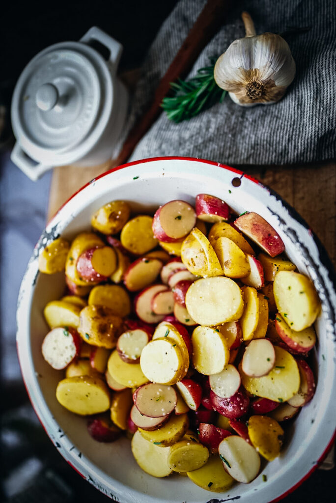 Sliced and seasoned potatoes, onions, garlic, and herbs that will be added to a roast beef.